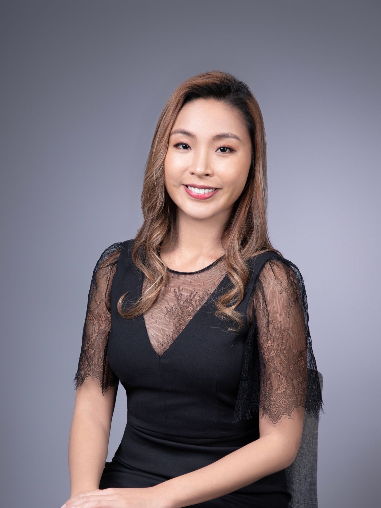 A smiling woman in a black lace dress